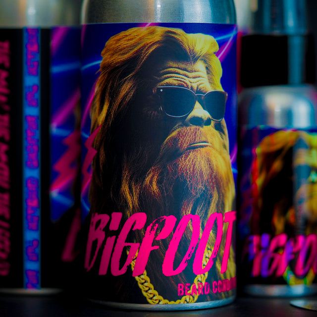 A bottle of Bigfoot beard conditioner on a table in front of other The Bearded Grenade beard products.
